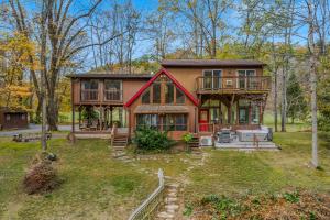a large house with a deck in the woods at River Time Cabin - Riverfront, Hot Tub, Screen Porch, Fishing, Games, View, 3 King Beds in Berkeley Springs