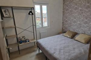 a bedroom with a bed and a brick wall at Gîte de l'Avenue Verte in Neufchâtel-en-Bray
