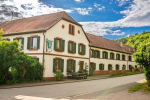 a large white building with green shutters on a street at Hotel Restaurant St. Germanshof in Bobenthal