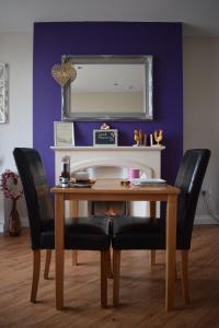a dining room table with two black chairs and a mirror at Barton Guest House in Barton upon Humber