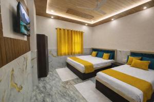 a hotel room with two beds and a tv at H0TEL PARBU KIRPAA Near Premanand Ji Maharaj Mandir Vrindavan in Chhatikara +6 photos