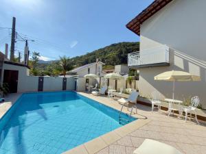 a villa with a swimming pool and a house at Studio VI até 7 pessoas em Juquehy in São Sebastião