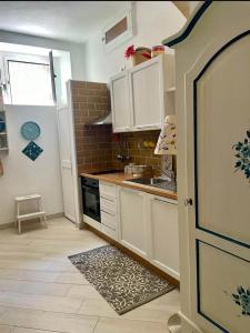 a small kitchen with white cabinets and a sink at Donna Sicilia Ortigia in Syracuse