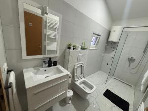 a white bathroom with a sink and a toilet at Apartman Rose in Čapljina