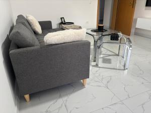 a living room with a gray couch and a glass table at Apartman Rose in Čapljina