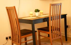 a black table with two chairs and two candles on it at FLAT 2 Seven Cambrian Square First Floor Flat in Newtown