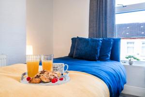 a tray of food on a bed with two glasses of orange juice at 2 Bedroom 5 Single Beds WiFi in Northampton +40 photos