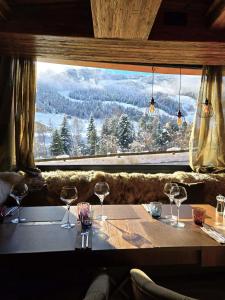 a table with wine glasses in front of a large window at Hotel Vall d'Isard Suites in El Tarter