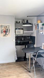 a kitchen with a table and a microwave at Studio cosy à deux pas de Paris in Clichy