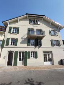 a large building with green shutters and a balcony at Zogbi Hospitality Aubonne 3 in Aubonne