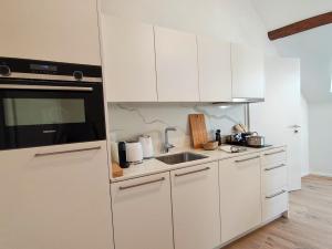 a kitchen with white cabinets and a sink at Zogbi Hospitality Aubonne 3 in Aubonne