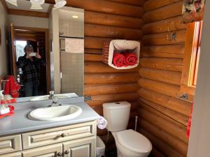 a woman taking a picture of a bathroom with a toilet and sink at Montana Hill Guest Ranch in Bridge Lake +170 photos