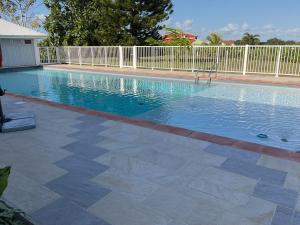 a swimming pool with a white fence around it at Bungalow Cécilia in Petit-Bourg