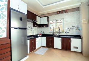 a kitchen with white cabinets and a stainless steel refrigerator at Pepa's villa and homestay in Khadkagaon