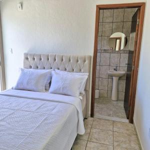 a bedroom with a bed and a sink and a mirror at Refúgio Aura,casa com suíte, wi-fi, garagem e churrasqueira in Aparecida