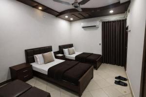 a bedroom with two beds and a ceiling fan at Al Huda Hotel in Multan