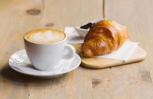 a cup of coffee and a croissant on a table at Moonlight Etna B&B Catania in Catania
