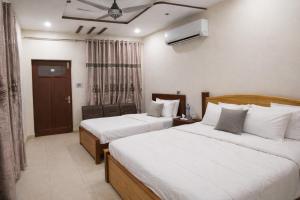 a hotel room with two beds and a window at Al Huda Hotel in Multan