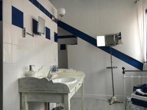 La salle de bains est pourvue d'un lavabo et d'une bande bleue sur le mur. dans l'établissement Le Prieuré Boutefol, à Surville