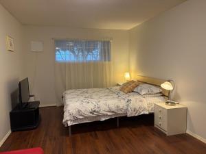 a bedroom with a bed and a television and a window at Lovely suite in Burnaby