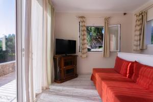 a living room with a red couch and a tv at Villa Odyssey Verde in Dassia