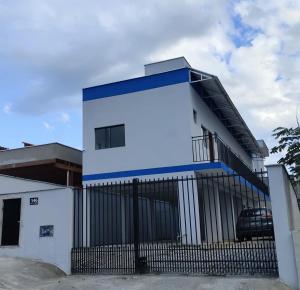 a white and blue building with a black fence at Studio com Ar condicionado, Boa Localização, Internet Rápida 2 in Joinville