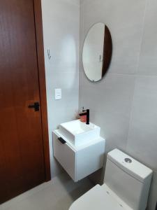 a bathroom with a toilet and a sink and a mirror at Studio com Ar condicionado, Boa Localização, Internet Rápida 2 in Joinville +16 photos