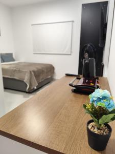a room with a desk and a bed and a table with a plant at Studio com Ar condicionado, Boa Localização, Internet Rápida 2 in Joinville