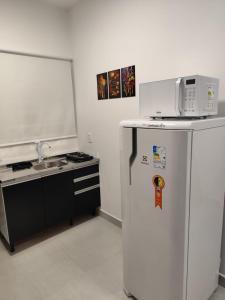 a kitchen with a microwave on top of a refrigerator at Studio com Ar condicionado, Boa Localização, Internet Rápida 2 in Joinville