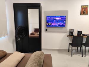 a living room with a couch and a tv on a wall at Studio com Ar condicionado, Boa Localização, Internet Rápida 2 in Joinville