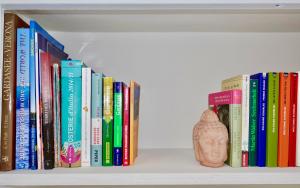 a row of books on a shelf with a vase at casa prima vista in Torri del Benaco