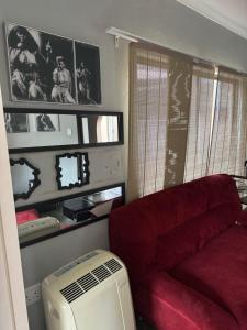 a living room with a red couch and a fan at Virginia Town House in Mthatha
