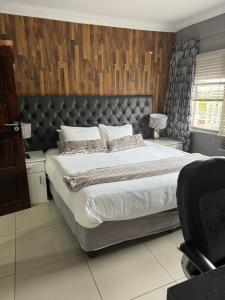 a bedroom with a large bed with a leather headboard at Virginia Town House in Mthatha