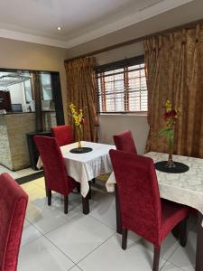 a dining room with two tables and red chairs at Virginia Town House in Mthatha