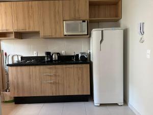 a kitchen with a white refrigerator and a microwave at Apto vista in Ponta Grossa