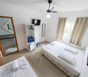 a white bedroom with a bed and a mirror at Hotel Santo Afonso in Aparecida