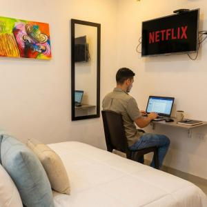 a man sitting at a desk with a laptop at Apartaestudios Galanni in Valledupar