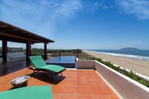 a patio with a green chair and a view of the beach at Stunning, Oceanfront Casa de Olas in Ixtapa-Zihuatanejo International +11 photos