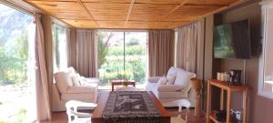 a living room with white furniture and a large window at Red Hill Lodge Purmamarca in Purmamarca
