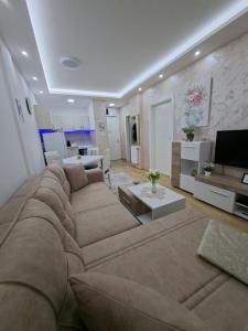 a living room with a large couch and a television at Apartman TRI KRALJA 4 in Banja Koviljača