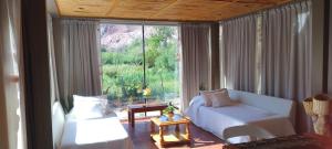 a living room with a bed and a couch and a window at Red Hill Lodge Purmamarca in Purmamarca