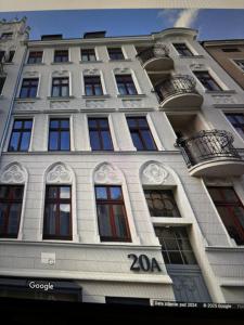 a tall white building with windows and balconies at Rybaki Sauna & Jacuzzi Apartment in Poznań