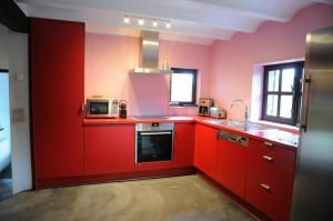 a red kitchen with a sink and a microwave at Holiday Home Poppenhuis in Durbuy