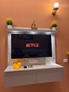 a flat screen tv on a wall with a netflix sign at Good vibes only gaur city center studio apartment in Ghaziabad