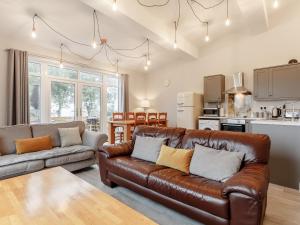 a living room with a leather couch and a kitchen at The Barn-Uk32860 in Neath