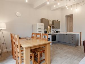 a kitchen and dining room with a wooden table and chairs at The Barn-Uk32860 in Neath
