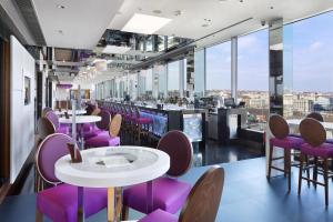 a restaurant with purple chairs and tables and windows at Hilton Prague Atrium in Prague