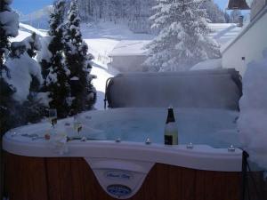 a hot tub with a bottle of wine in a snow covered yard at Apartment Höfer by Interhome in Schröcken