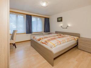 a bedroom with a bed and a chair and windows at Apartment Wohnung Muntegn by Interhome in Vicosoprano