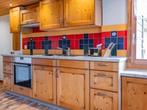 a kitchen with wooden cabinets and red and blue tiles at Apartment Haggen by Interhome in Oberegg